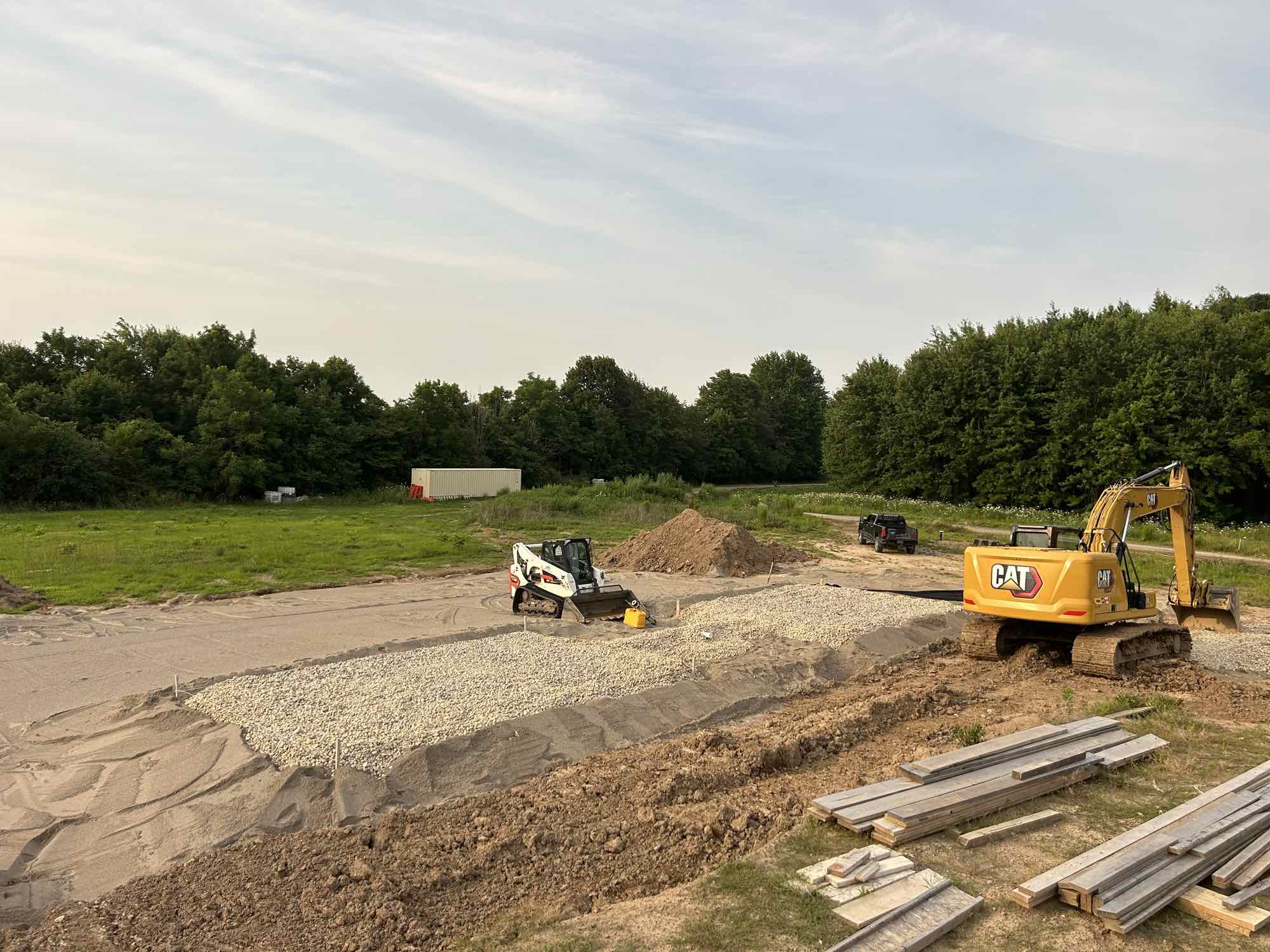 Country Estates Construction septic installation: septic bed of clear stone on filter fabric, with an excavator and skid steer