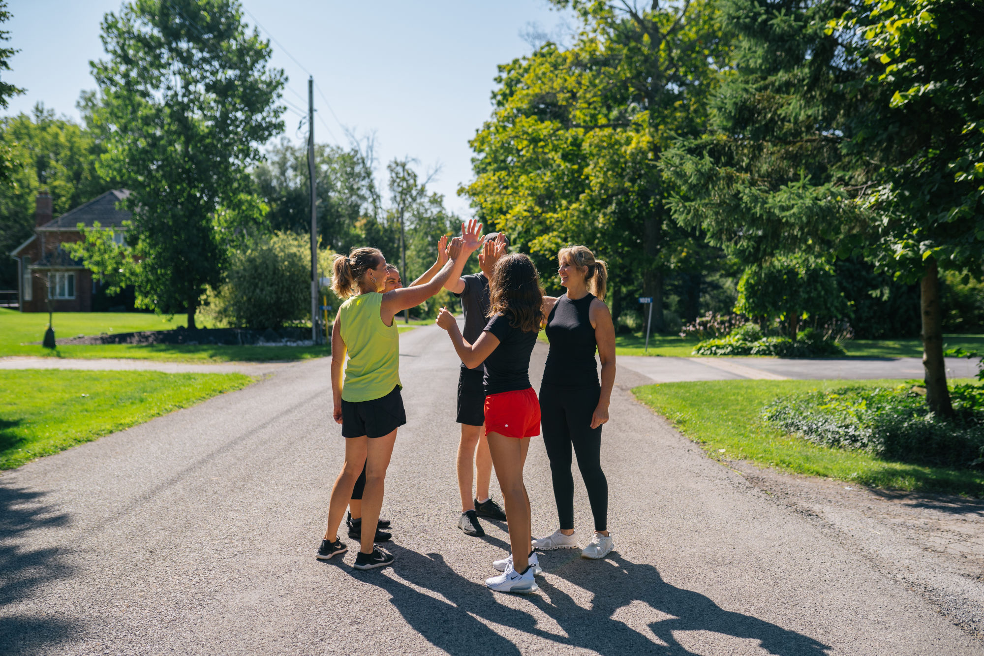 Kaley and clients high-fiving on a sunny country road after a workout