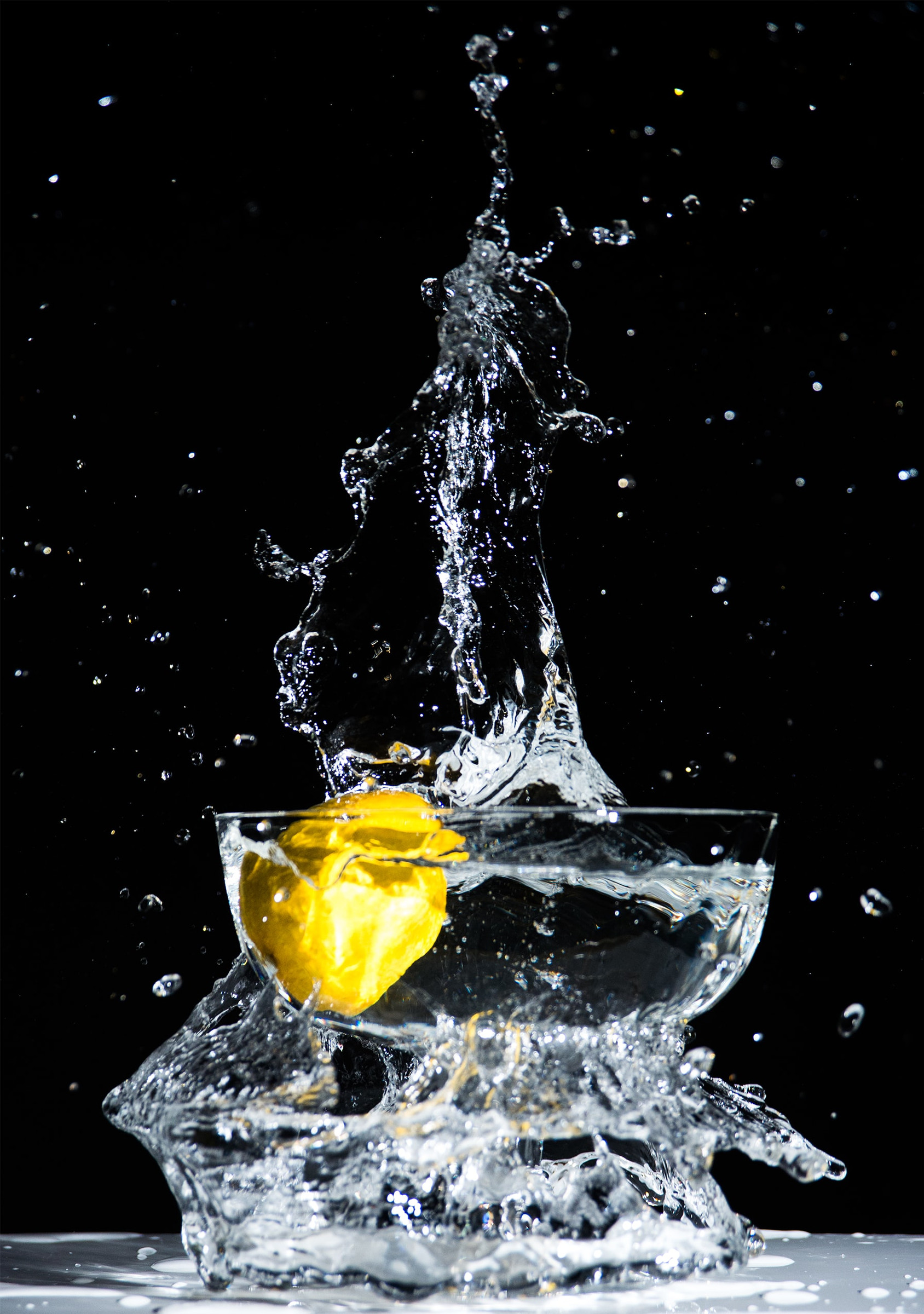 A lemon splashing into a glass of water