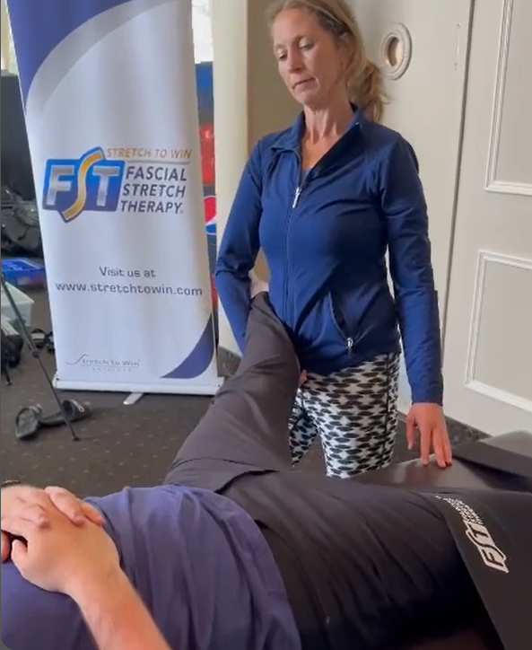Kaley beside her Fascial Stretch Therapy banner