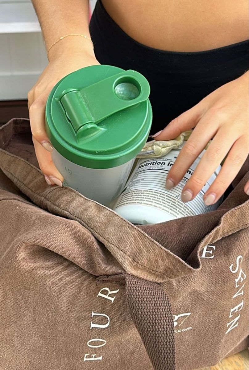 A green shaker cup and Arbonne protein in a tote bag