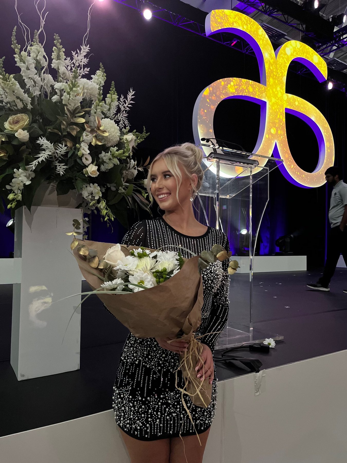Meg on stage at an Arbonne event, holding a bouquet
