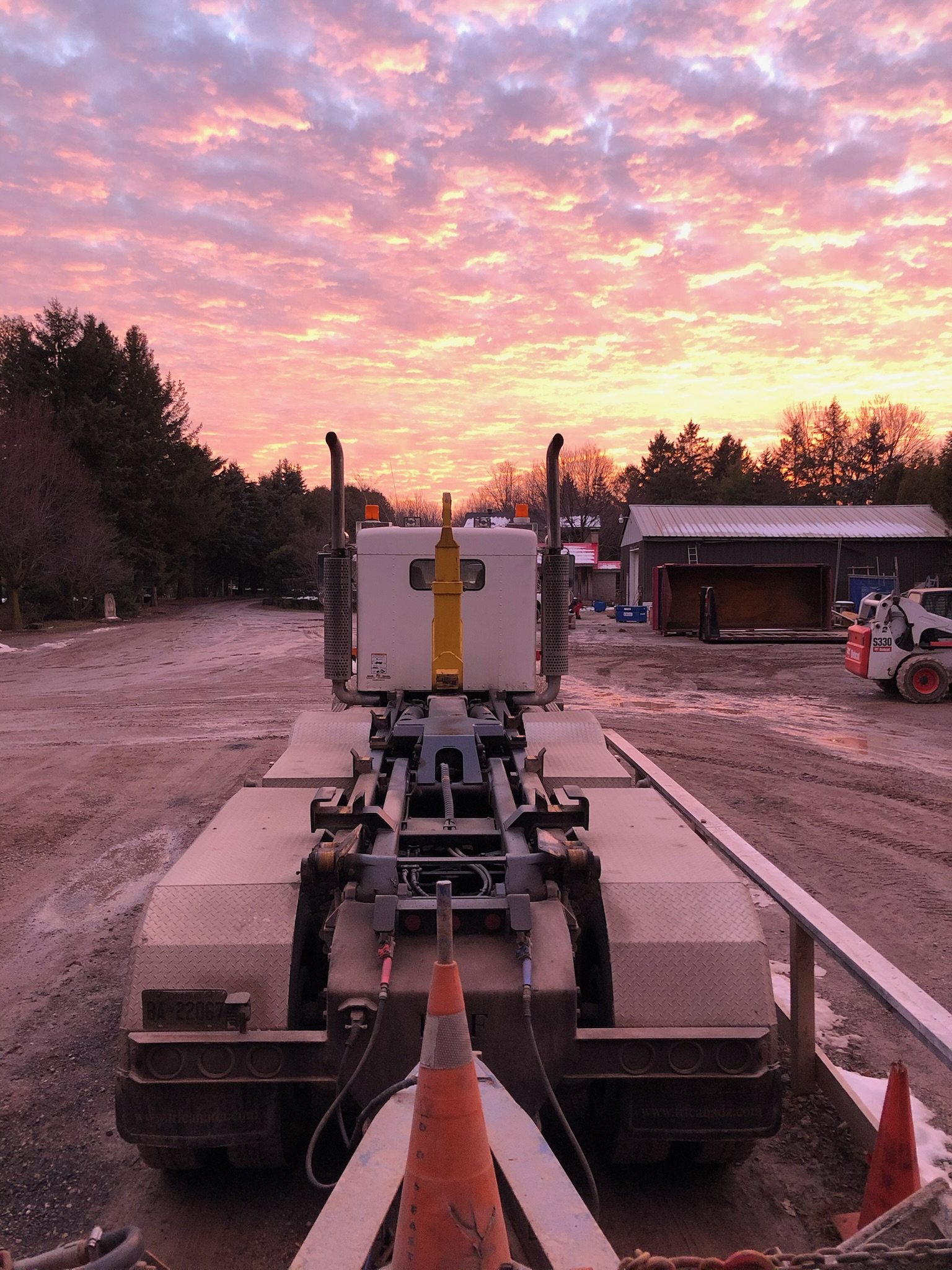 Truck and float trailer under a pink morning sky