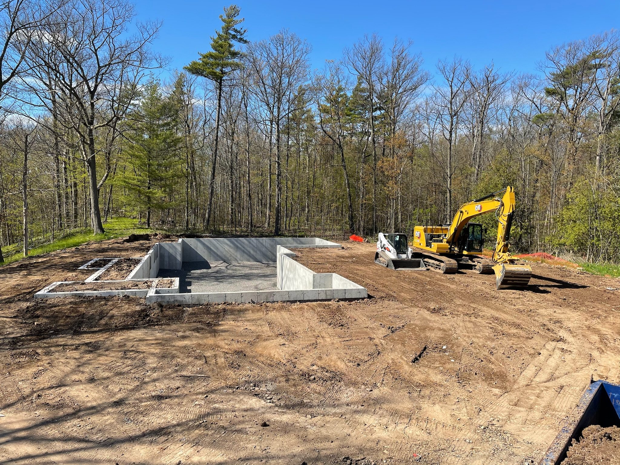 Excavator on a cleared, wooded building lot