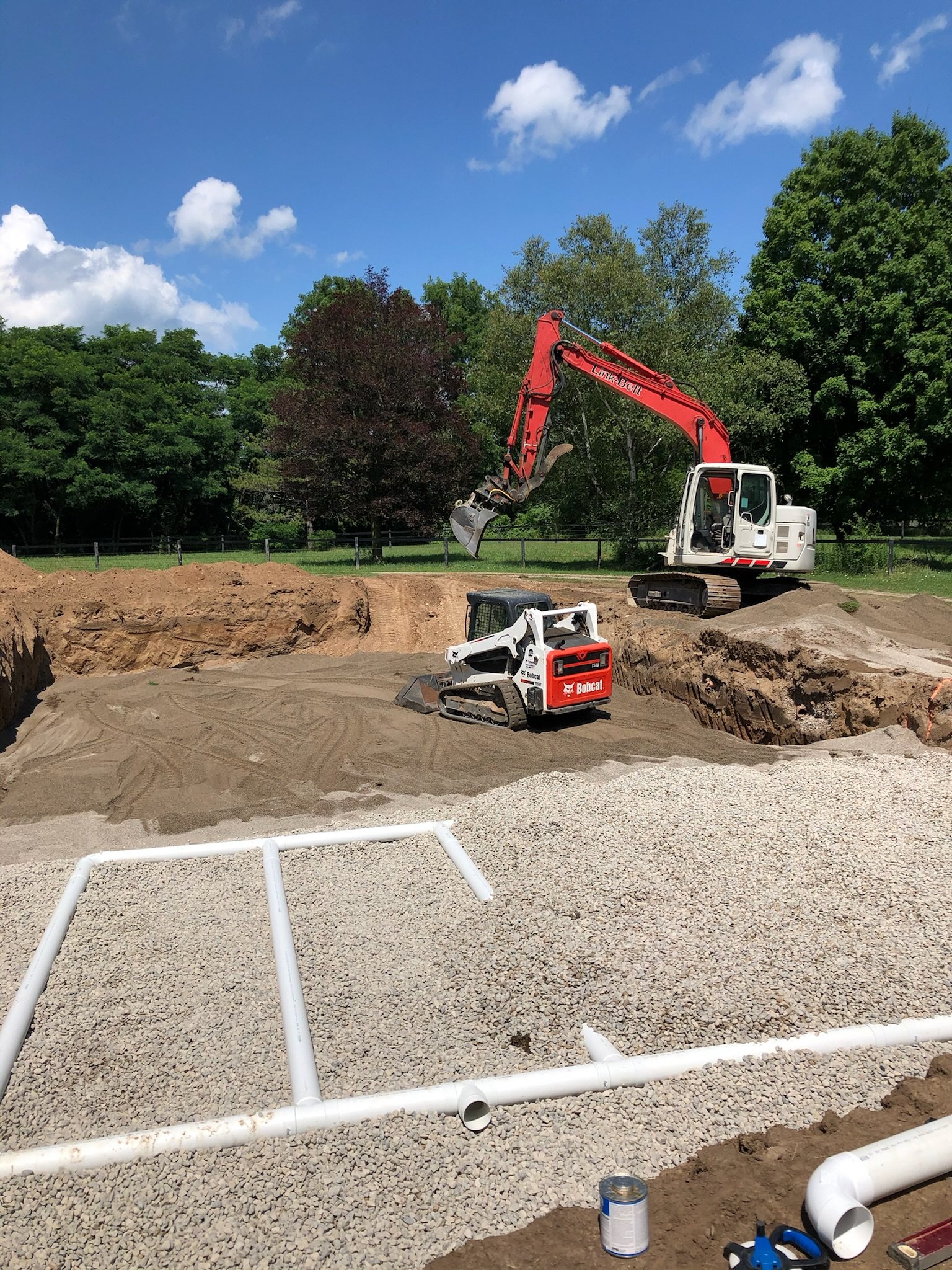 Septic bed laid out on clear stone, with an excavator and track loader