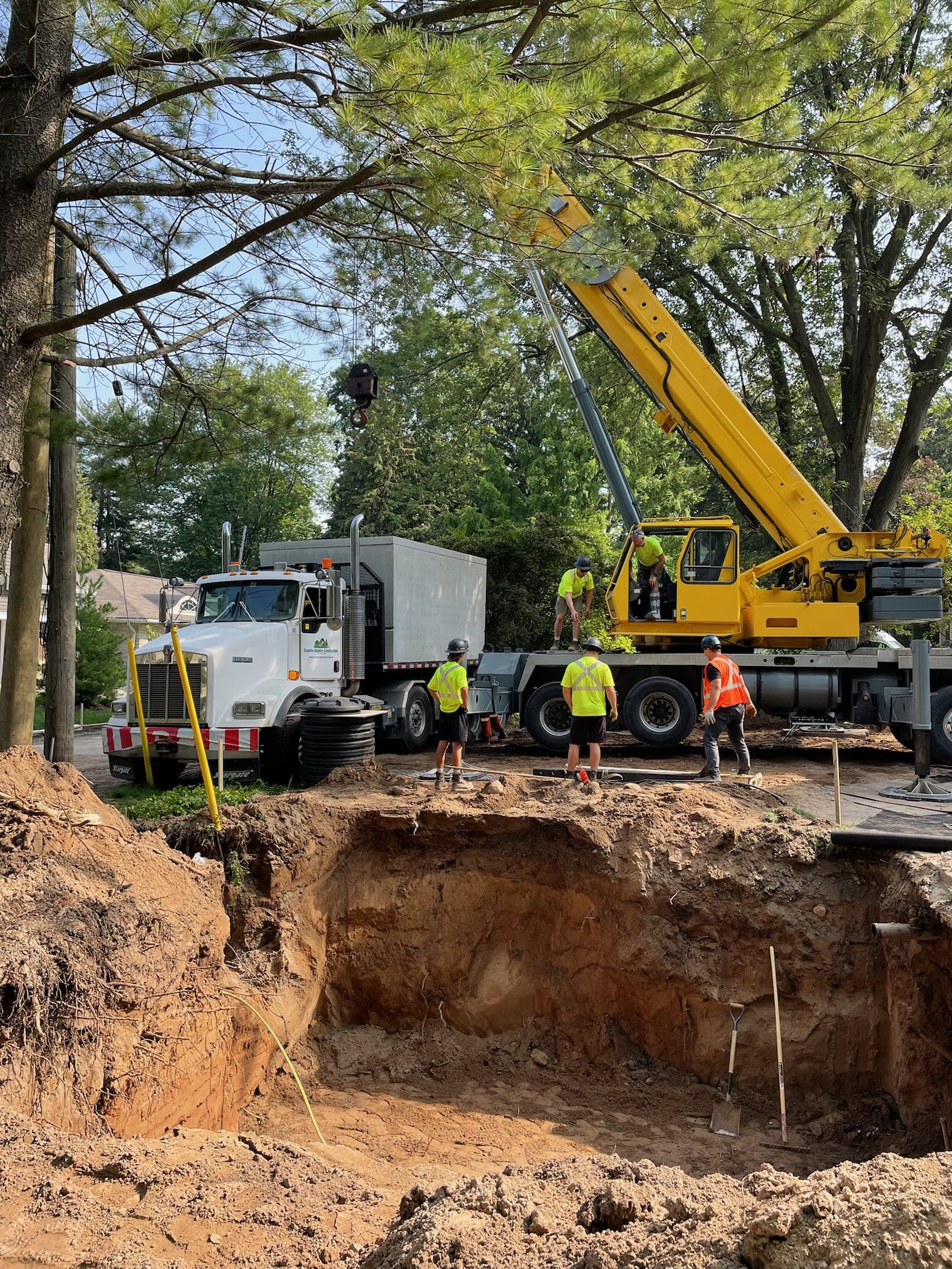 Crane truck and crew beside a deep excavation