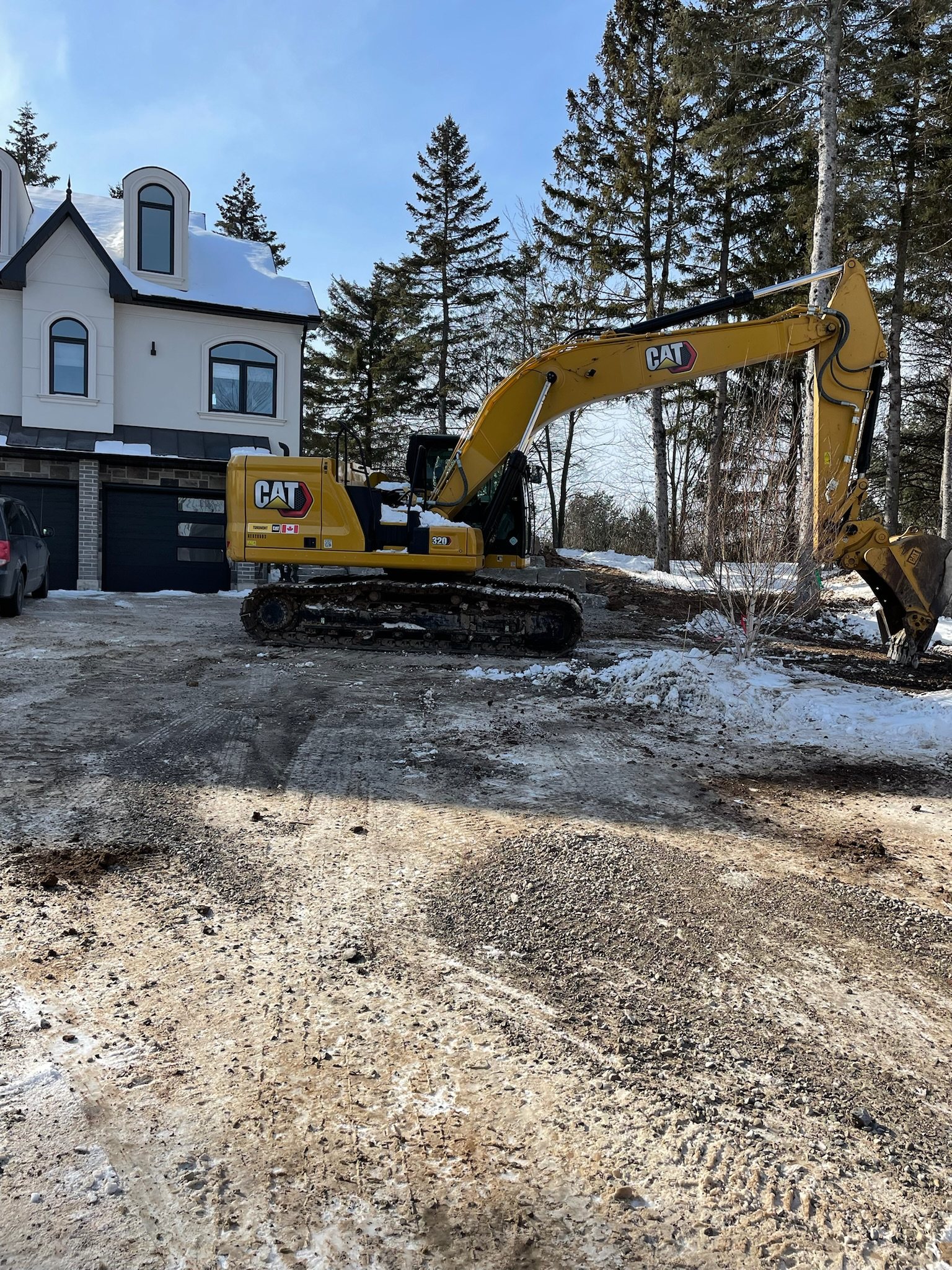 Excavator at work in front of a new house in winter