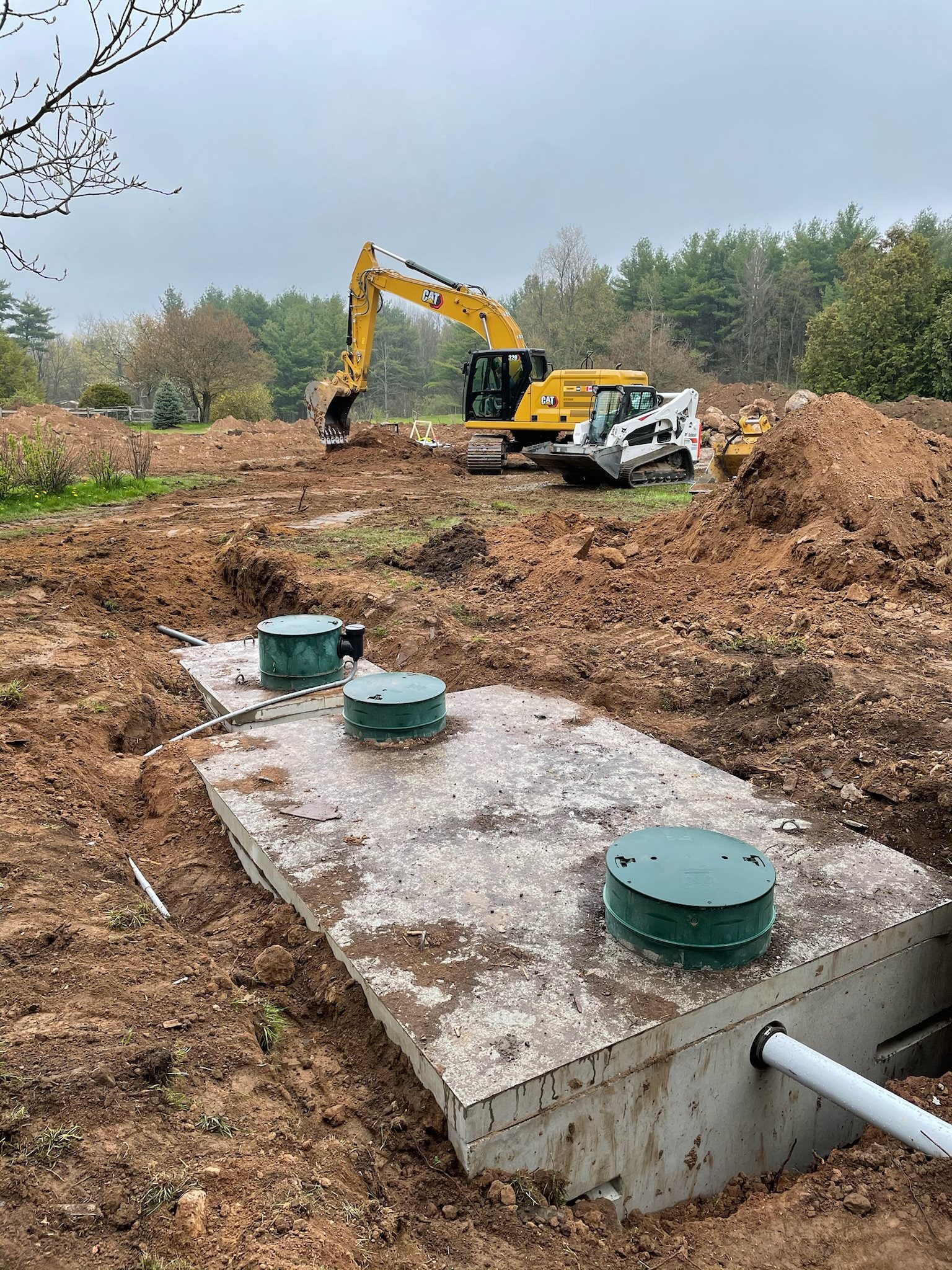 Concrete septic tank with three access lids, set and ready for backfill