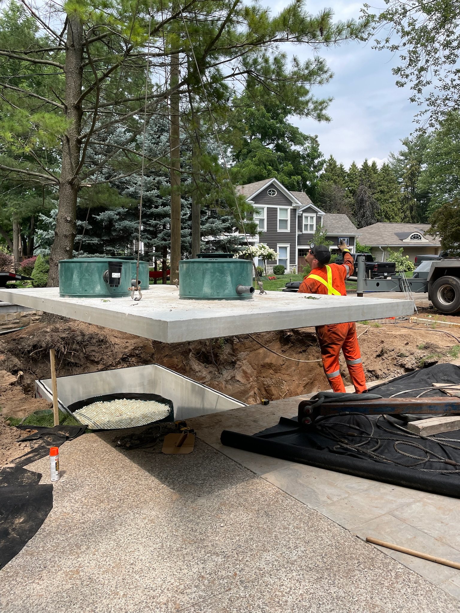 Concrete tank with green risers lowered into place beside a house