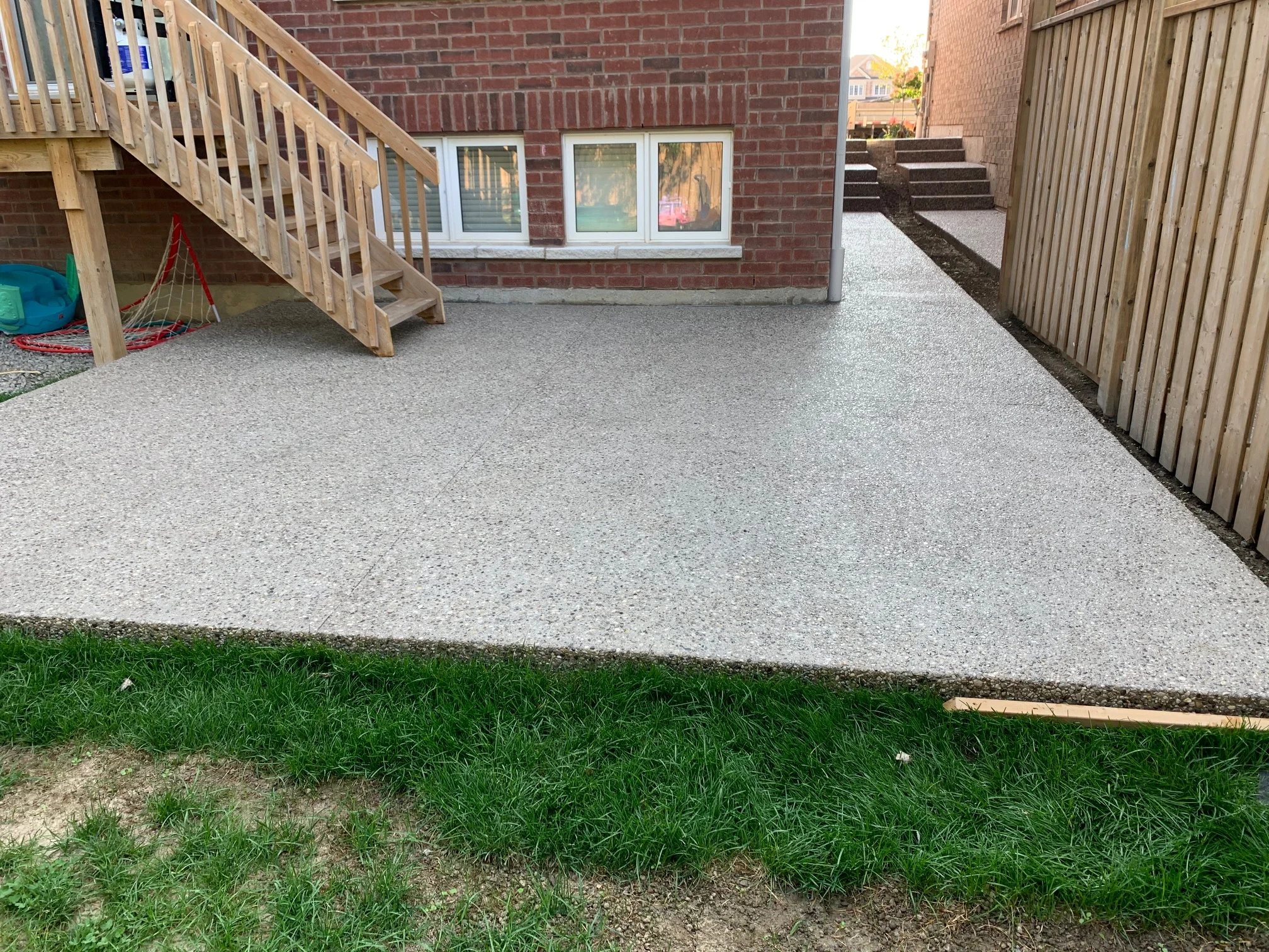 Exposed aggregate concrete patio beside a house