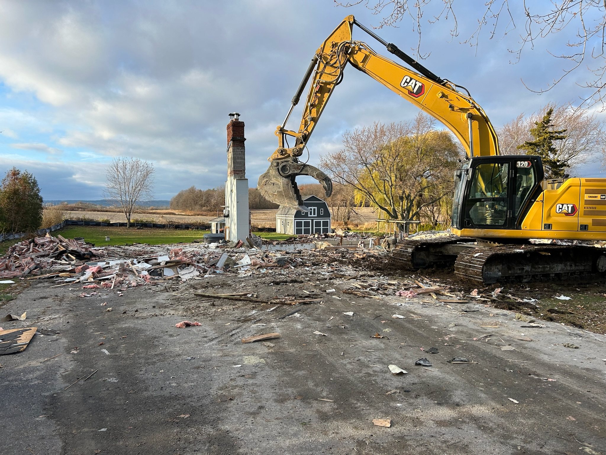 Excavator clearing the last of a demolished house
