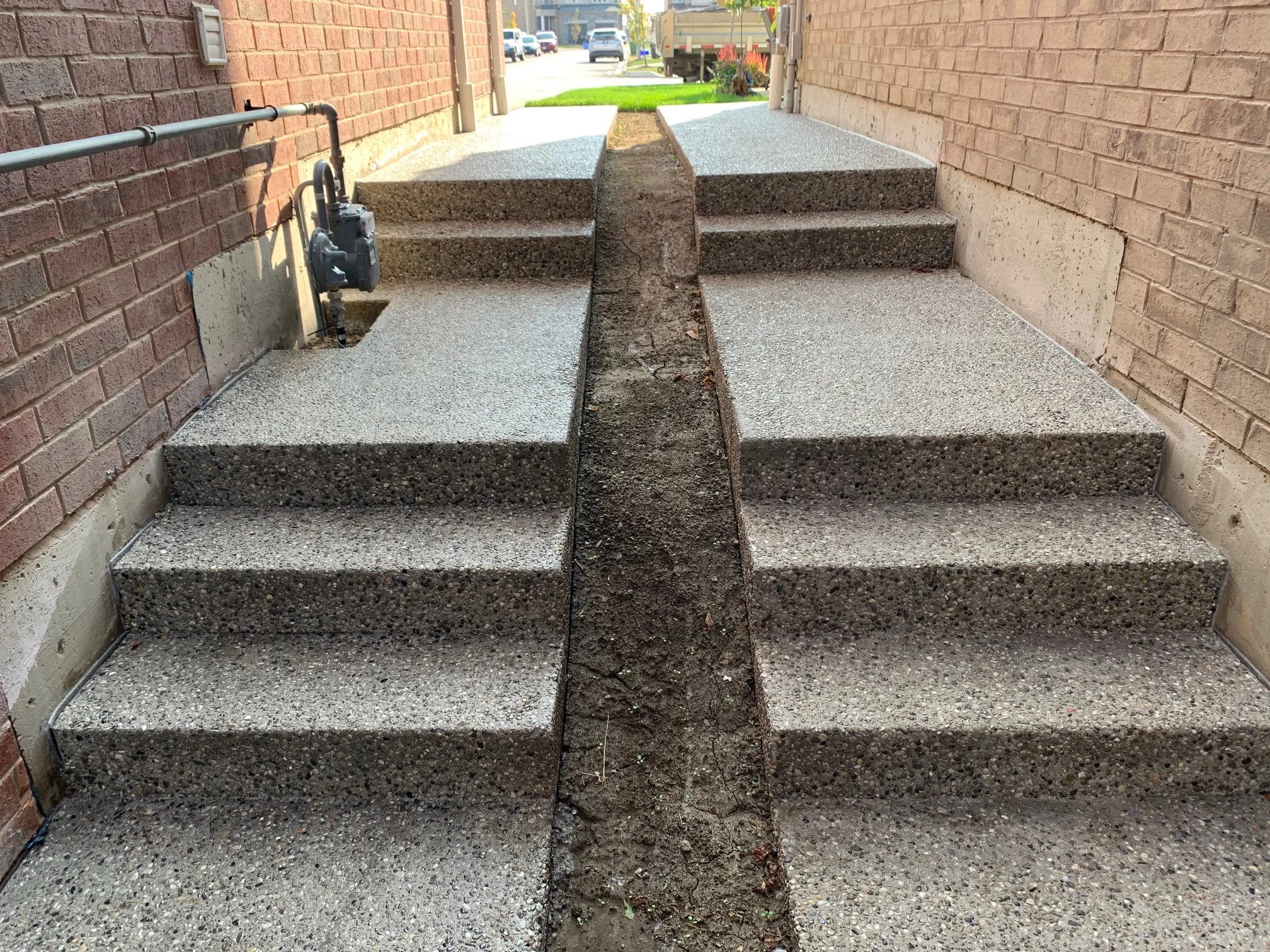 Exposed aggregate concrete steps between two brick walls