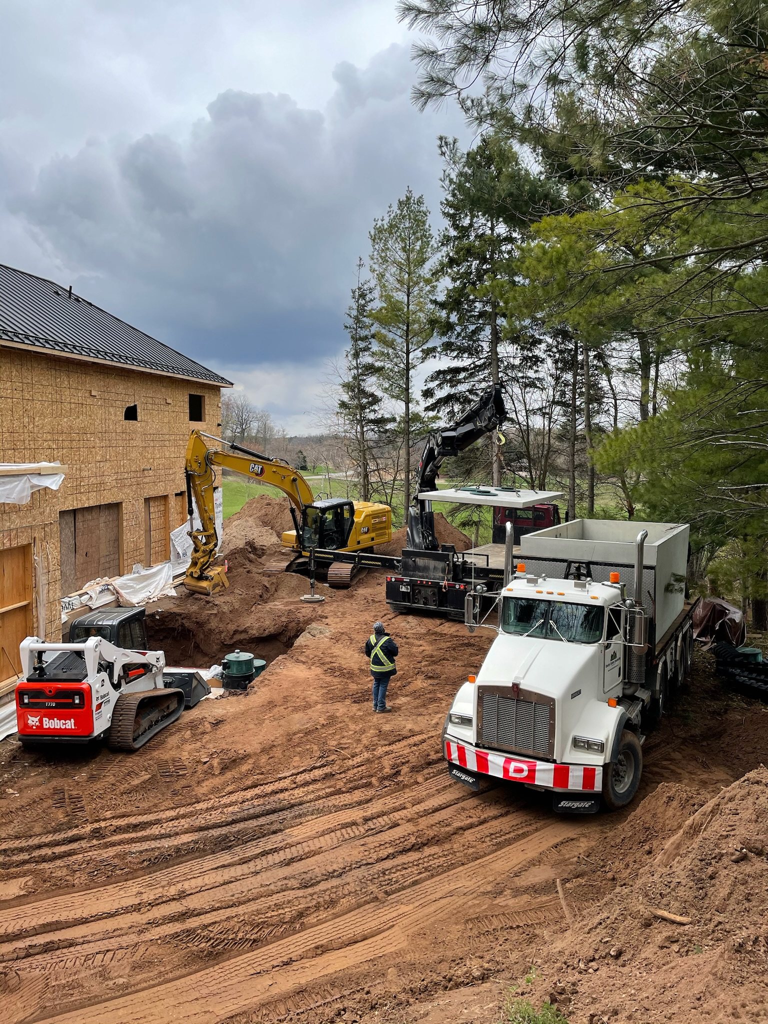 Crane truck, excavator and track loader on a septic installation