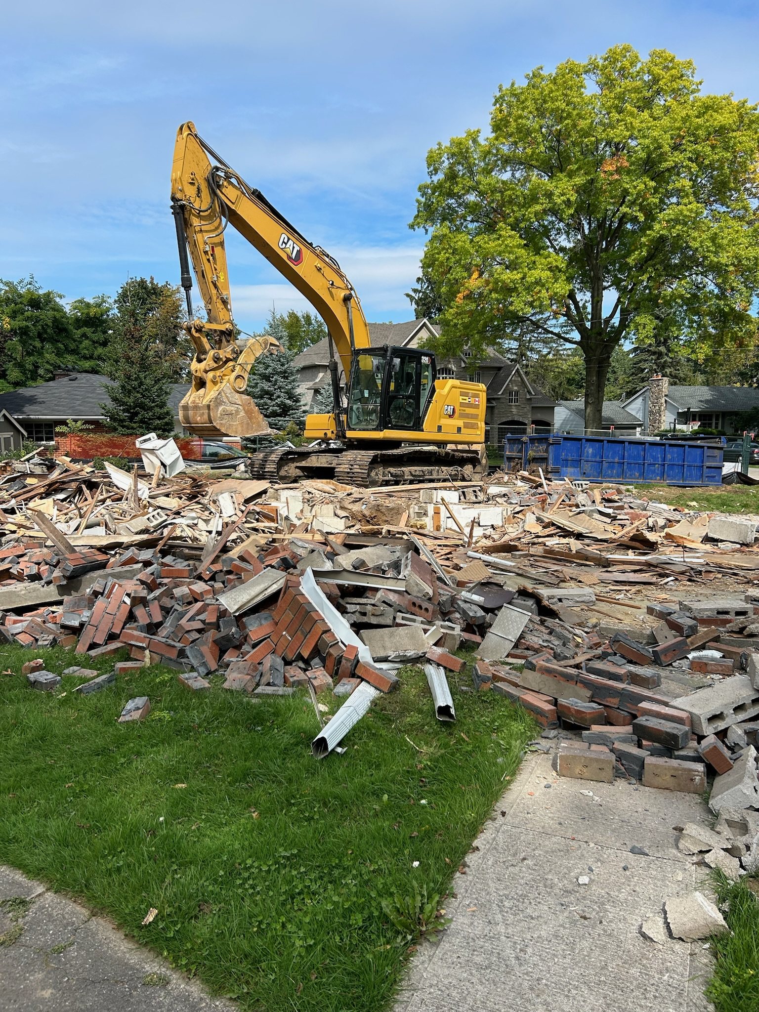 Excavator and disposal bins at a brick house demolition