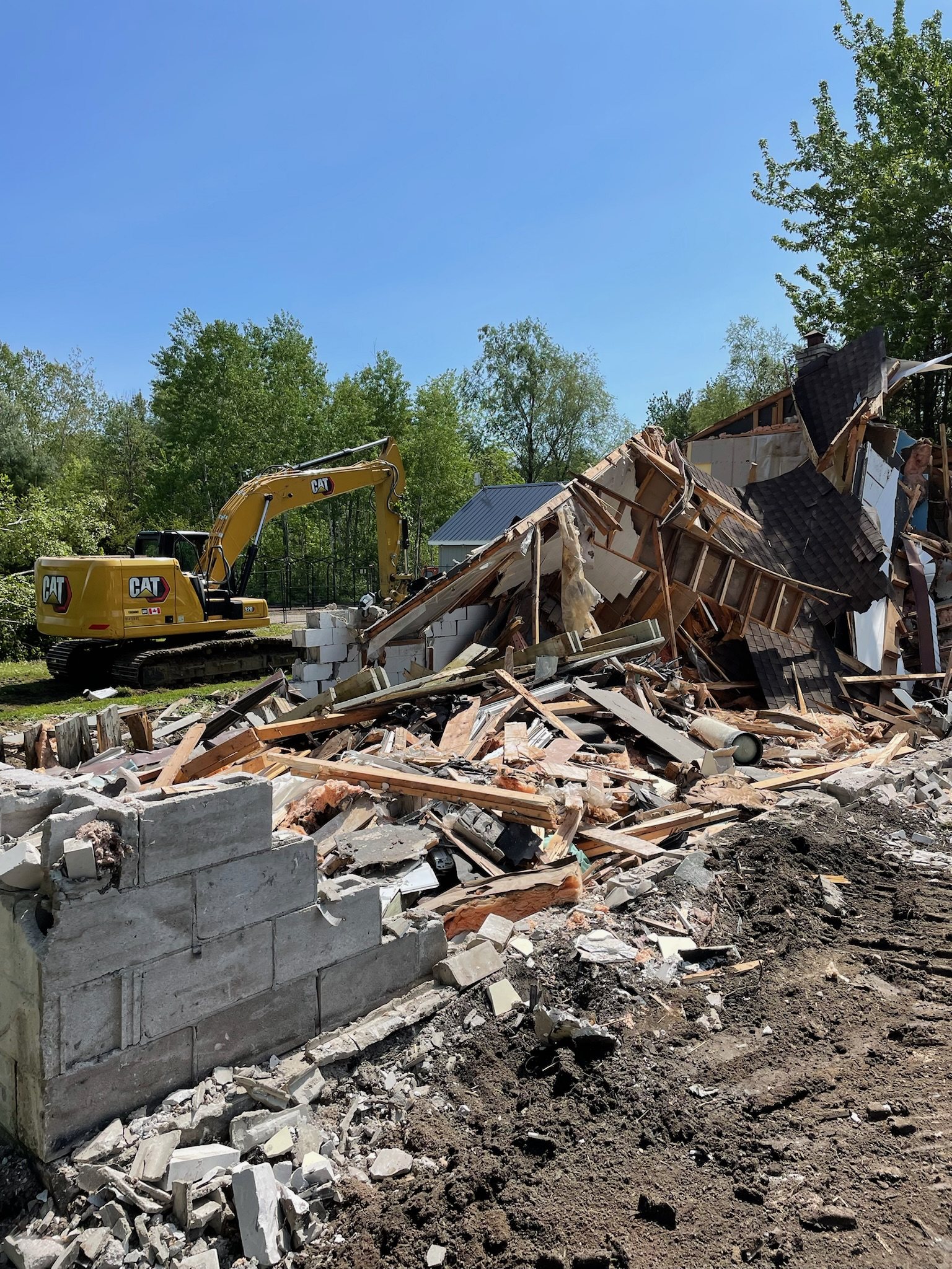 Excavator demolishing a house down to its foundation