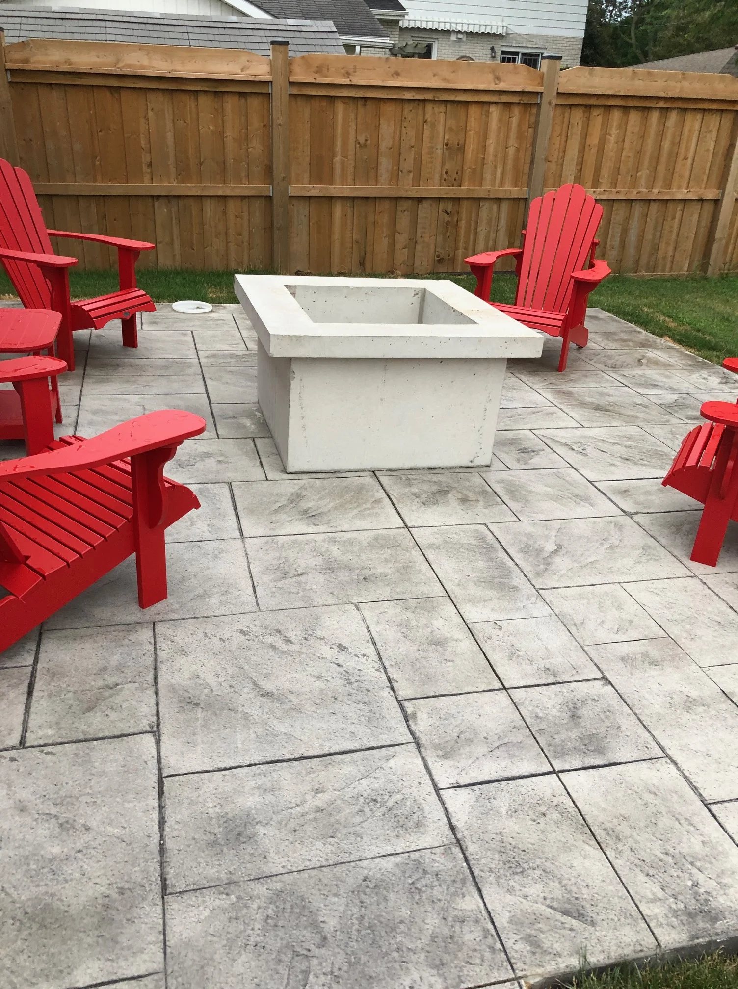 Stamped concrete patio with a fire table and red chairs