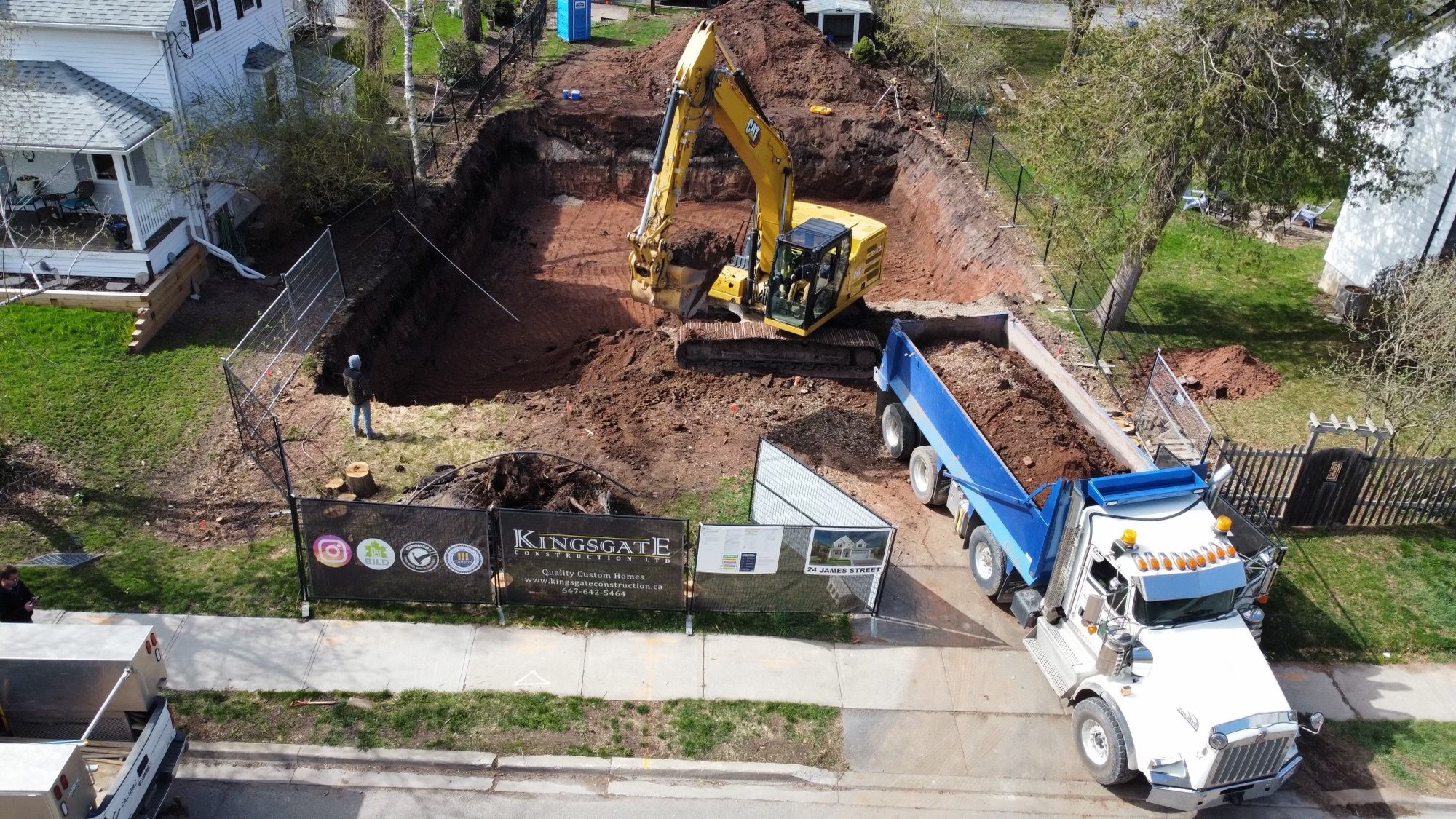 Aerial view of an excavator and a dump truck at a house lot excavation