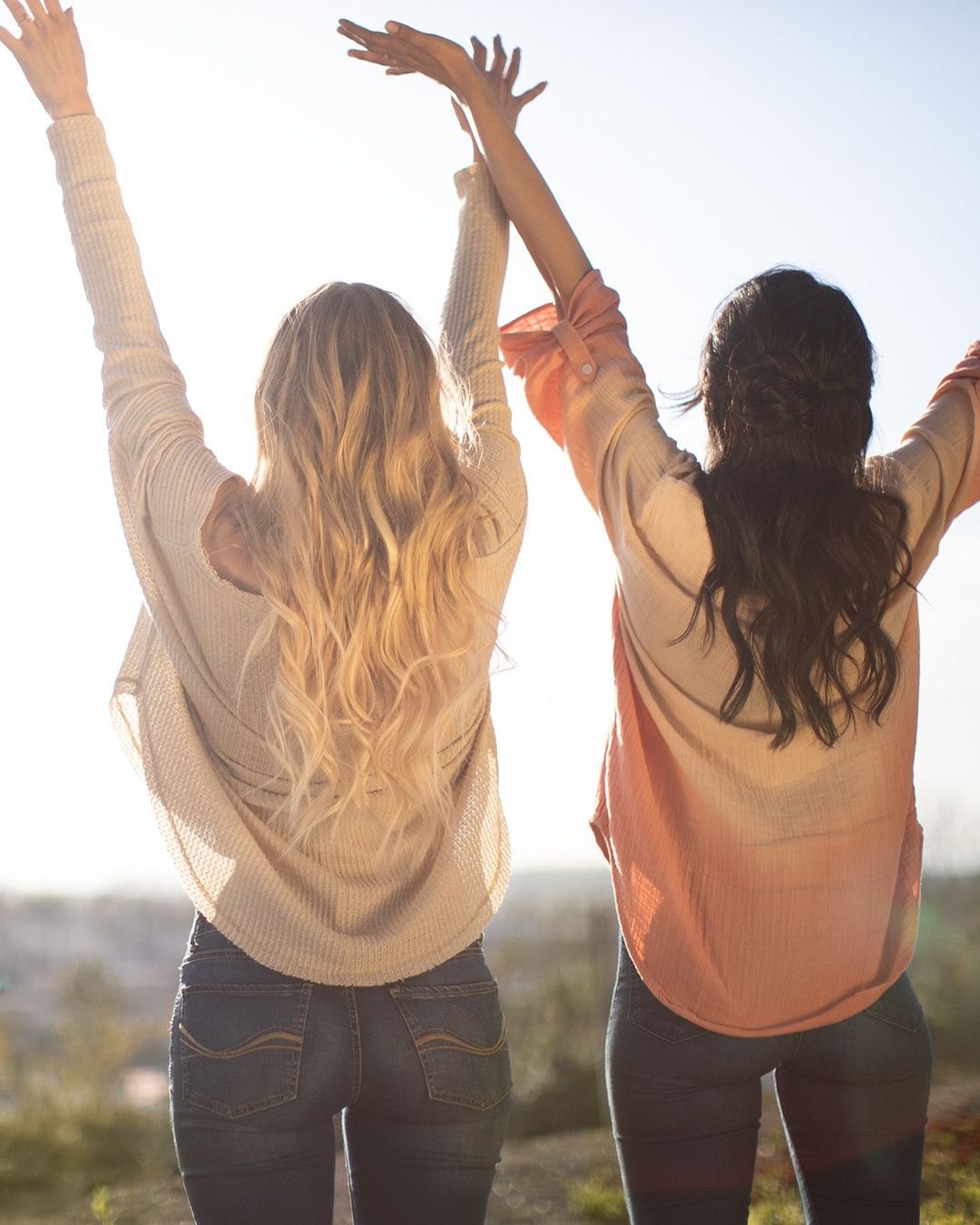 Two friends with their arms up at sunset